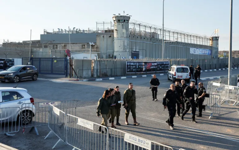 Security officials walk outside the Israeli military prison, Ofer, on the day Israel is expected to release Palestinian prisoners as part of a hostages-prisoners swap and a ceasefire deal in Gaza between Hamas and Israel, near Ramallah, in the Israeli-occupied West Bank, October 13, 2025. REUTERS/Ammar Awad